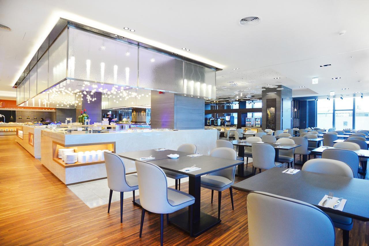 Caesar Metro Taipei Hotel Bagian luar foto The photo shows a modern restaurant interior. It features contemporary design elements, including sleek, minimalist furniture with light-colored chairs and dark tables. The layout includes several dining tables arranged in a spacious setting. 

In th